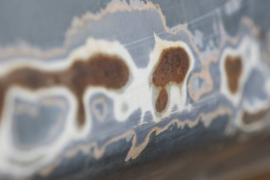 Metal yüzeydeki pas ve korozyon hasarının soyut arkaplanı. Soyulmuş boya yıpranmış dokuyu ortaya çıkarır, melankolik çürüme ve unutulmuş zamanı.