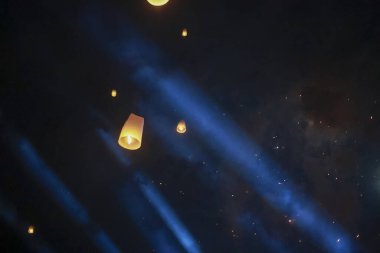 Gece festivalinde sihirli gökyüzü feneri. Umut dolu sarı ışık, parlak bir ışık demeti ile koyu mavi gökyüzüne karşı parlıyor. Huzur ve kutlama sahnesi yaratıyor.