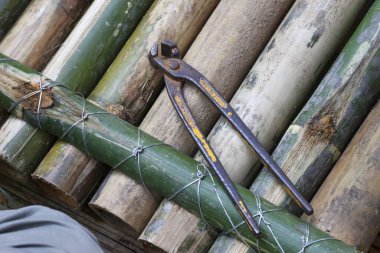 Kırsal bambu yapısına dayanan eski kıskaç aleti. Doğal malzemelerle el yapımı ve çalışma sürecini gösteren sessiz bir el yapımı ve inşa anı