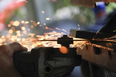 Elektrikli aletlerle endüstriyel işler kesme ve sıcak çeliği öğütme. Metal kesme işleminden çıkan parlak turuncu kıvılcımlar gibi yoğun metal çalışmalarını gösteriyor.