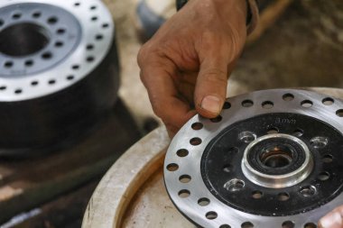 Motosiklet tamiri üzerinde çalışan kararlı bir tamirci. Yetenekli hizmet, bakım için garaj ayarlarına metal fren diski yerleştirmeyi içerir