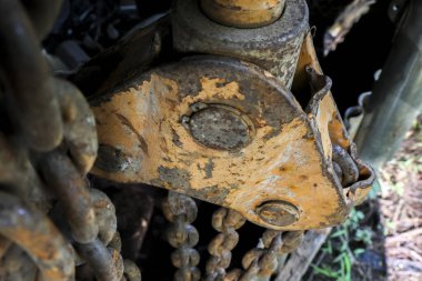 Ağır makinelerdeki yıpranmış ve paslı sarı metal eklemlere yakından bakın. Eski, aşınmış endüstriyel ekipmanlar, ağır çelik zincirler, belirgin aşınma izleri gösteriyor.