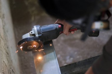 Atölyede metal öğütücü aletle metal öğütüyor. Yoğun endüstriyel süreç el emeği sırasında parlak kıvılcımlar yaratır, iş yoğunluğunu gösterir