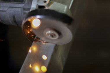 Endüstriyel öğütücü alet, atölyede metal öğütme sırasında sıcak kıvılcımlar oluşturuyor. Bu güçlü süreç dönen diskten gelen yoğun sürtünme ve ısı gösteriyor