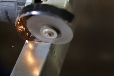 Kıvılcımlar saçarak metali kesen bir açı öğütücüsüne yaklaş. Atölyedeki bu endüstriyel araç, metal işçiliği ve üretiminin gücünü ve hassasiyetini gösteriyor.