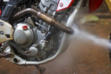 Kirli motosiklet motorlarını yüksek basınçlı çamaşır makinesiyle yıkamak tatmin edici. Su püskürtme rutin off-road motor bakımında çamur ve kiri temizler.