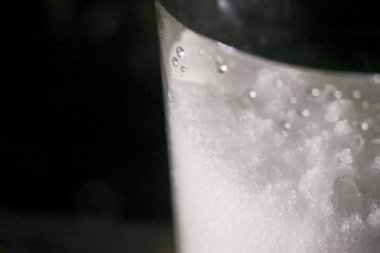 Makro cam kaptaki beyaz kristal tuzu kapat. İçeriğin dokusunu ve detaylarını gösteren siyah arkaplanlı minimalist ve soyut görünüm