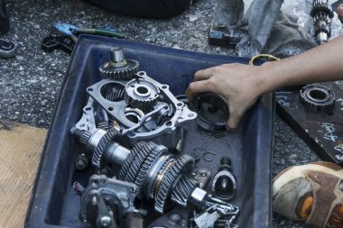 Odaklanmış mekanik el, parçalanmış otomotiv şanzıman vites kutusu üzerinde çalışır. Garajdaki tamir ve bakım hizmetleri sırasında her metal teçhizatı dikkatlice taşır.