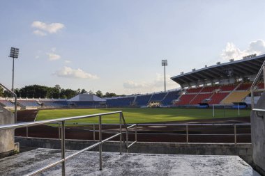 Yeşil çayırı, koşu yolu ve mavi gökyüzünün altında renkli stantları olan sakin, boş bir stadyum. Barışçıl açık hava spor arenası bir spor müsabakası ya da etkinlik bekliyor