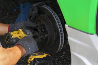 Eldivendeki odaklanmış tamirci el araba freni tamir hizmeti veriyor. Atölyede elektrikli aletle profesyonel bakım, disk üzerinde ayrıntılı çalışmaları gösterir