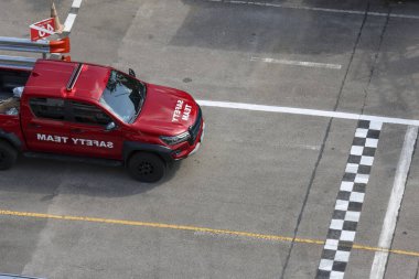 Asfalt yarış pistindeki güçlü kırmızı kamyonet bitiş çizgisine yaklaşıyor. Yarışın heyecanı ve hızına odaklanmış heyecan verici bir motor sporu yarışması