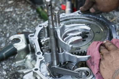 Odaklanmış tamirci motor tamir ve onarım hizmeti veriyor. Kirli ellerin açık vites kutusunu kumaşla temizlerken detaylı görüntüsü