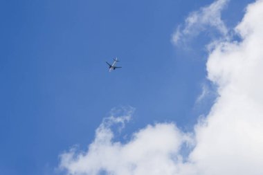 Güneşli bir günde beyaz bulutlu güzel mavi gökyüzünde bir uçak. Yolculuk ve seyahat için yüksek uçuşlar sırasında özgürlük ve macera hissi