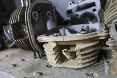 Sökülmüş motor bloğunun atölyedeki tezgahta silindir başlı görüntüsünü kapat. Kirli metalik bölüm mekanik onarım veya bakım sürecini gösterir