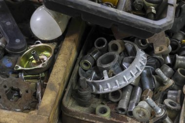 Dağınık garaj veya atölyedeki eski paslı metal parçalarını kapatın. Fındık, cıvata ve bilyelerin de dahil olduğu dağınık endüstriyel çöp yığını kirli bir his yaratıyor.