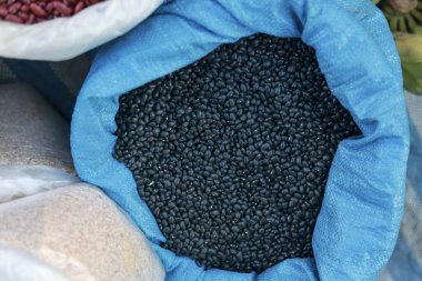 Markette içi çiğ siyah fasulye dolu büyük mavi çuvalı kapat. Bu sağlıklı, organik malzeme, temel gıda, satışa hazır. Sahne doğal ve bol geliyor.