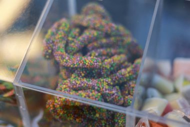 Şeffaf çöp kutusuna şeker serpiştirilmiş renkli şeker solucanının neşeli yakın görüntüsü. Şekerci dükkanında satılık bu eğlenceli, lezzetli tatlı atıştırmalığı