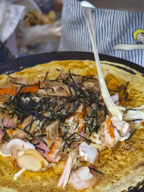 Lezzetli krep, esnek peynir ve ızgarada pişirilmiş yosun. Lezzetli Asya sokak yemekleri yerel marketteki satıcı tarafından yapılıyor.