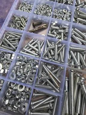 Plastik bölme kutusunda çeşitli somunlar, civatalar, vidalar ve vidalar içeren organize metal donanım koleksiyonunu kapat.