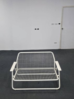 Beyaz minimalist sandalye, modern mobilyaların bir parçası, saf iç kısımda duruyor. Boş bir odadaki bu yalnız tasarım sessiz bir tefekkür hissi uyandırıyor.