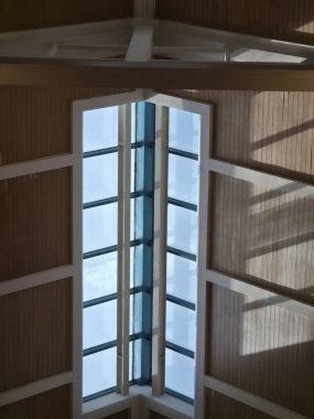 Geometrik tavan ve duvar tasarımının yer aldığı modern iç mimariye bakın. Köşedeki pencereden gelen parlak ışık güçlü bir gölge deseni ve huzurlu bir ruh hali yaratır.