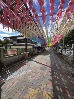 Açık hava sahnesi neşe ve kültürel kutlamayı çağrıştırıyor, sayısız renkli fenerle canlı sokak dekorasyonu güzel bir festival atmosferi yaratıyor parlak mavi gökyüzü, büyüleyici bir şekilde aşağı iniyor.