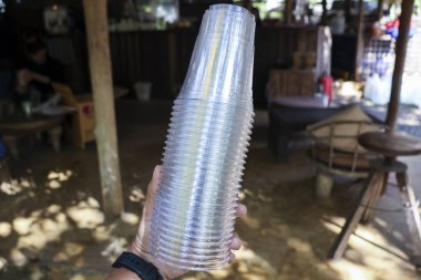 Tek kullanımlık plastik bardaktan oluşan büyük bir yığın tutan kişi. Açık hava partisinde ya da kırsal pazar etkinliğinde soğuk içecek servis etmek için basit bir hazırlık.