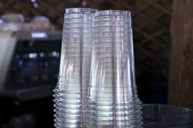 Parti için şeffaf, tek kullanımlık plastik bardak yığını. Boş içki takımı tezgahın üzerine yığılmış. Hayat arkaplanı içecek servisi için hazır olan ögeyi gösteriyor