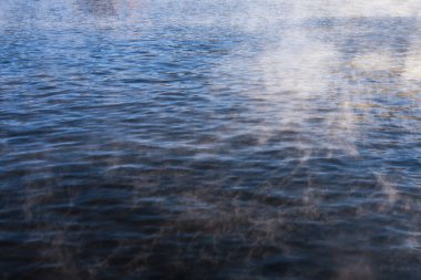 Sakin, mavi bir arka plan, dingin bir sis ve yüzeyden yükselen bir buhar. Huzurlu, huzurlu, ruhani duygularla dolu bir doğa sahnesi. Meditasyon için mükemmel.