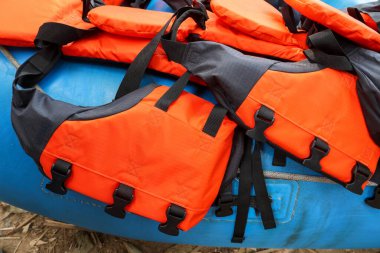 Parlak turuncu can yeleği ve çelik yelek mavi şişirilebilir bir salda su sporu macerası için hazır ve güvende hissetmenizi sağlıyor.