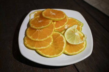 Taze dilimlenmiş portakal ve limonlu narenciye. Sağlıklı beslenme ve yaşam tarzı için doğal ve enerjik hissetmek için koyu ahşap masada sağlıklı yiyecek atıştırmalığı.