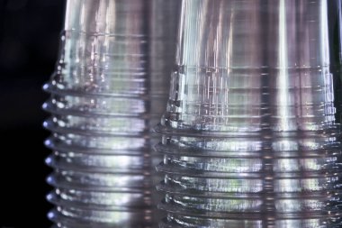 Plastik bardak istifinin makro ayrıntıları. Bu tek kullanımlık temiz ve şeffaf arka plan tekrarlanan şablon soyut, endüstriyel ve kısır bir his yaratır.