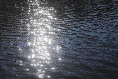 Güneş ışığı yansıması ile köpüklü su yüzeyi sakin ve barışçıl bir zemin oluşturuyor. Yumuşak dalgalı güzel mavi sıvı doku, sakin doğa konsepti için mükemmel.