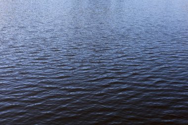 Yumuşak dalgalı sakin mavi su yüzeyi sakin ve sakin bir zemin oluşturur. Okyanus dalgasının derin mavi dokusu barışçıl ve soyut deseni oluşturur.