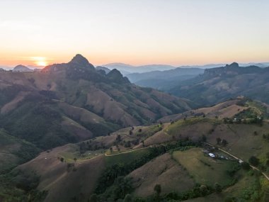 Güneşin doğuşuyla birlikte engin dağ manzarasının huzurlu, huzurlu havası. Güzel sabah gökyüzünün altında kayan tepeleri ve sisli vadileri gösteren manzaralı açık hava gezisi.