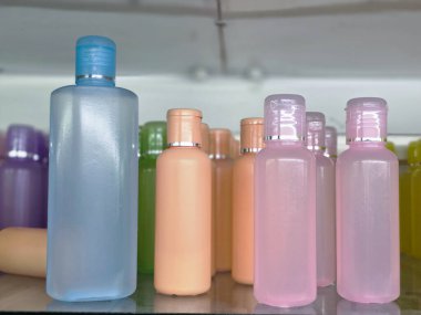 Raftaki sıvı ürün için renkli boş plastik kozmetik şişe kapları. Bu canlı ve düzenli koleksiyon güzellik ve hijyen için ambalaj kavramlarını gösteriyor.