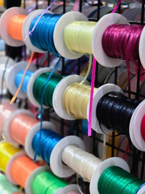Renkli iplik makaraları ve el işi projesi için kablo çeşitleri. Parlak dikiş malzemesi koleksiyonu bulanık arkaplan ile ekran rafında oturur