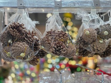 Noel alışverişinde bayram süsü olarak kullanılacak kozalak çantaları. Doğal ve kırsal el sanatları ürünleri mevsimsel kutlama için güzel, bulanık arka plan ışıklarıyla