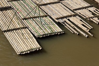 Çamurlu nehirde yüzen geleneksel bambu salının hava manzarası. Kereste endüstrisi için kırsal taşıma metodu sakin ve doğal bir şablon yaratıyor.