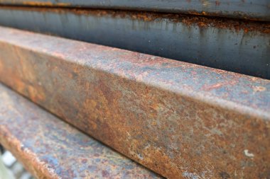 Paslı metal kirişin aşındırıcı kahverengi dokusuyla detaylandırılmış hali. Eski endüstriyel çelik çubuklar bir araya toplanmış. Çürüme hissi veren soyut bir arkaplan oluşturuyor.