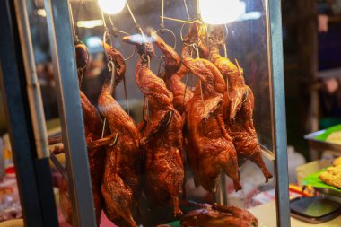 Asya 'daki sokak yemekhanesinde vitrinde asılı duran nefis kızarmış ördek. Bu iştah açıcı tavuk yemeği, ünlü Çin yemeği, geceleri altın ve lezzetli görünüyor.