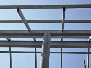 İnşaat halindeki çatıyı inşa etmek için sağlam metal iskelet yapısı. Çelik kiriş ve mimari çerçeve açık mavi gökyüzüne karşı ilerleme ve mühendislik tasarımı gösteriyor