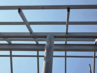 Mimari çelik çerçeve yapısı gri metal kirişli ve inşaat halinde. Bu endüstriyel şebeke, açık mavi gökyüzü arkaplanına karşı yapı iskeleti oluşturur