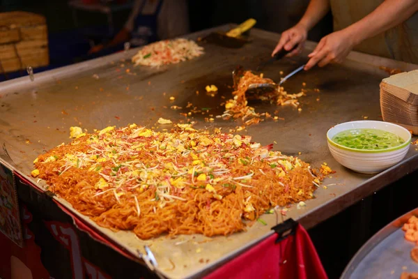 Tedarikçi geleneksel Asya usulü kızarmış erişte pişiriyor. Popüler sokak yemekleri. Gece pazarındaki sıcak teppanyaki ızgarasında yapılan bu iştah açıcı mutfak deneyimi otantik yerel mutfağı gözler önüne seriyor.