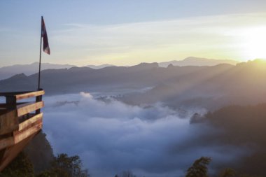 Gün doğumunda sakin ve manzaralı bir dağ manzarası. Aşağıda sis vadisi ve ufukta sıcak güneş olan engin bir manzara. Doğada gerçekten görkemli ve huzurlu bir an.