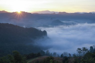 Vadide dingin bir sis denizi olan dağ manzarasının üzerinde güzel bir sabah güneşi doğuyor. Bu huzur verici, nefes kesici manzara doğanın huzur ve sakinliğini yaratır.