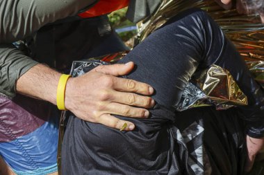 Duygusal insani yardım görevlisi elinde bakım desteği ile mülteci bacağı tutarken termal acil durum battaniyesine sarılmış kriz kurtarma görevinde umut ışığı konseptin kapanmasına yardımcı oluyor.