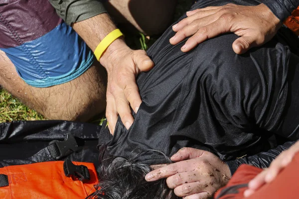 Ciddi bir kurtarma operasyonu esnasında yaralı bir yüzücünün omzunu tutan endişeli cankurtaranların yakın görüntüsü, siyah gömlekli baygın kurbana acil ilk yardım hizmeti veriyor.
