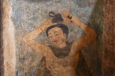 Tapınak duvarında yıpranmış eski bir duvar resmi var. Geleneksel kadın figürlü, kollarını kaldırmış, saç stili düzeltmiş, yüzünde huzurlu, mutlu, duygusal bir ifade var.