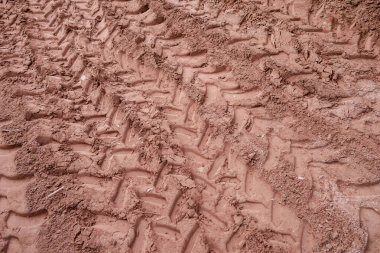Kahverengi çamur desenli derin lastik izleri ve ağır araç tekerleklerinin izleri kırsal alanda engebeli arazi ve kırsal bölgelerde kaba bir desen oluşturuyor.